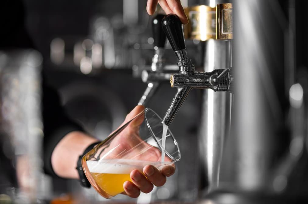 hand holds a glass and fills it with beer on a blurred background